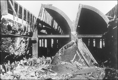 Military and civilians alike seek to make some sense of the works after its wartime attacks from the air.  Such damage led to shifting more production to the sub-story.